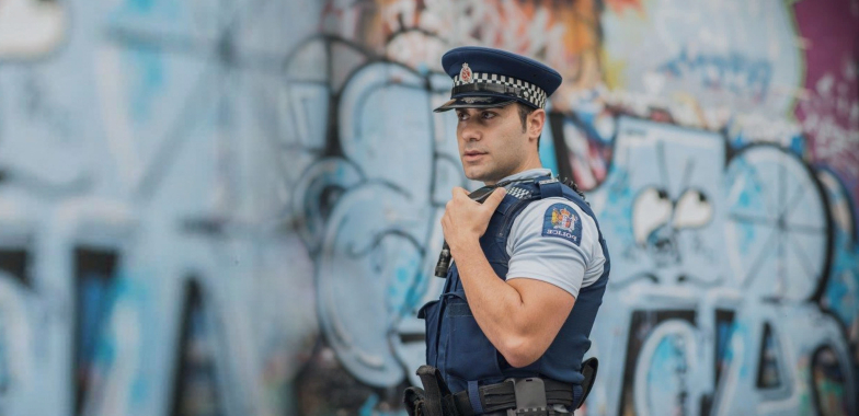 NZ Police officer in front of wall in urban area