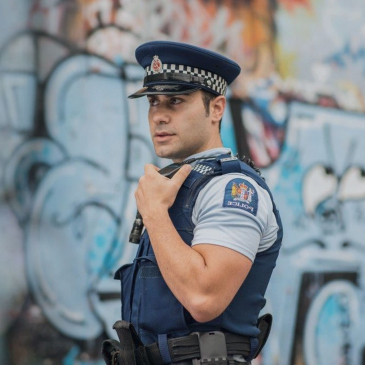 NZ Police officer in front of wall in urban area
